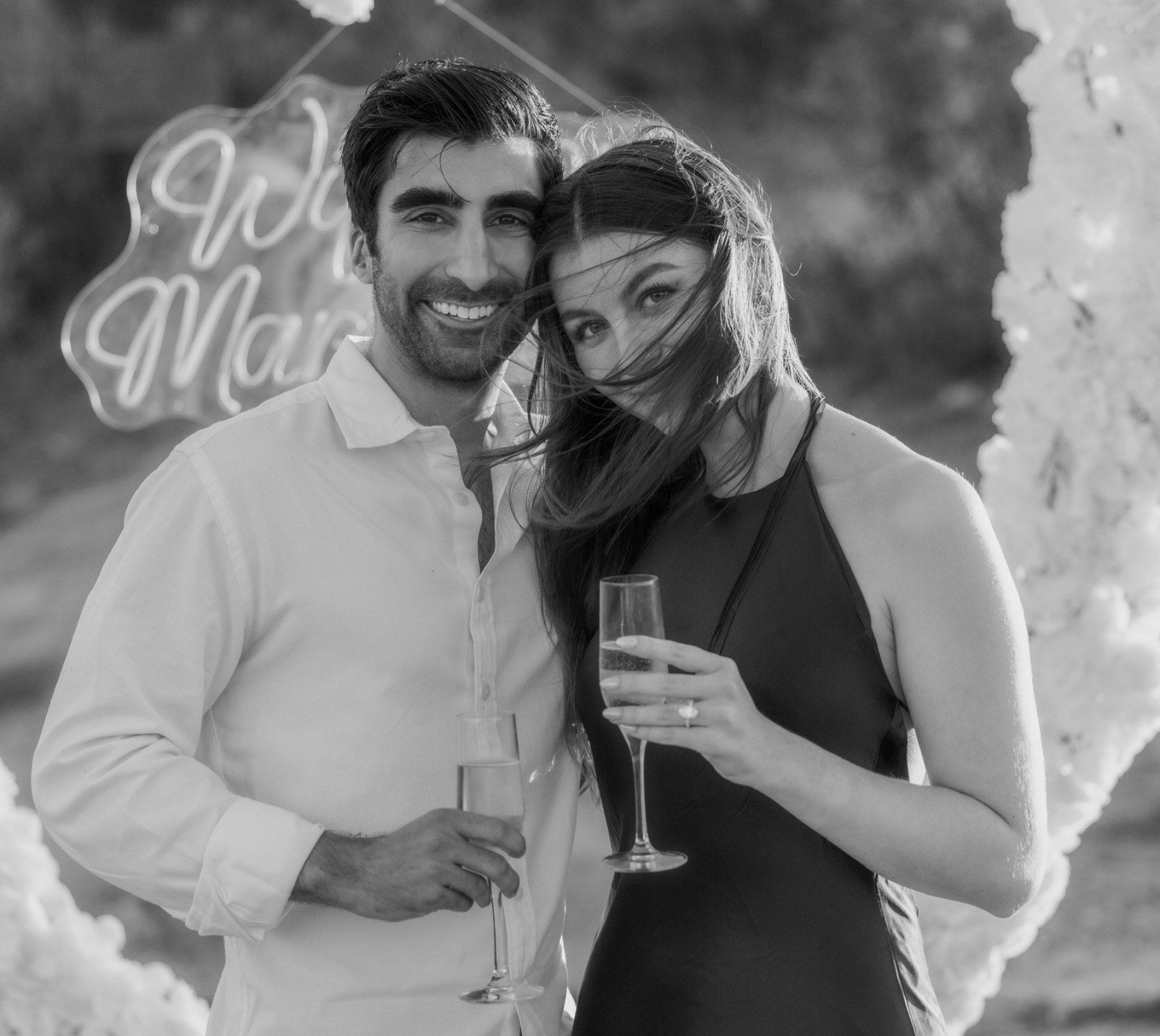 Black-and-white portrait of Cate and Brij celebrating with drinks